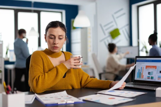 Passo a passo prático de como fazer gestão financeira da empresa 1 Mulher analisando relatórios financeiros com gráficos no escritório, representando como fazer gestão financeira eficiente.