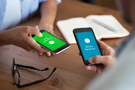 Duas pessoas segurando celulares realizando transações financeiras. Representando como receber pagamento pelo WhatsApp.